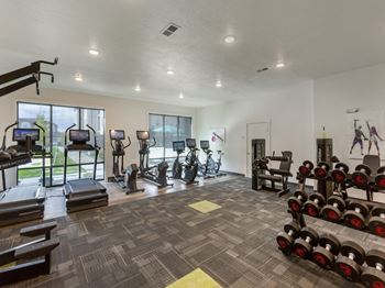 a spacious fitness center with cardio equipment and windows at Matheson Apartments in Tremonton UT